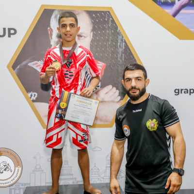 Mark Ghambaryan on the 1st place podium after winning the Gokor Chivichyan Cup in Grappling (34kg, 10–11 years), joined by coach Mayis Nersesyan