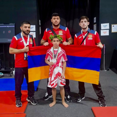 IMMAF World silver medalist Mark Ghambaryan with his coaches Artur Zakaryan and Mayis Nersesyan, standing proudly in front of the Armenian flag